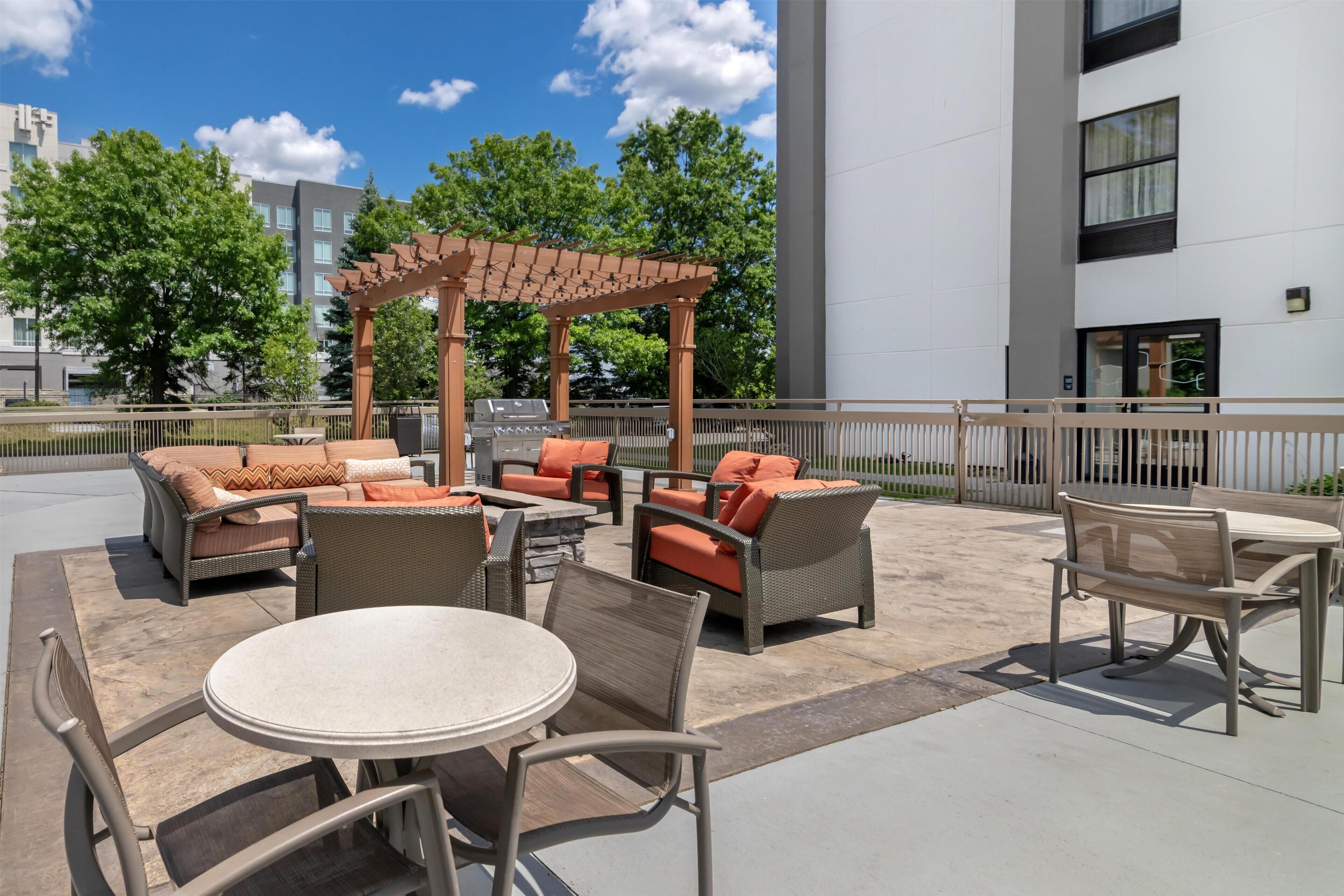 An outdoor patio area with wicker furniture, a pergola, and a barbecue grill.