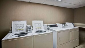 A laundry facility with three washing machines and two dryers, arranged in a row. - Hampton Inn Albany-Wolf Road (Airport) (Albany)