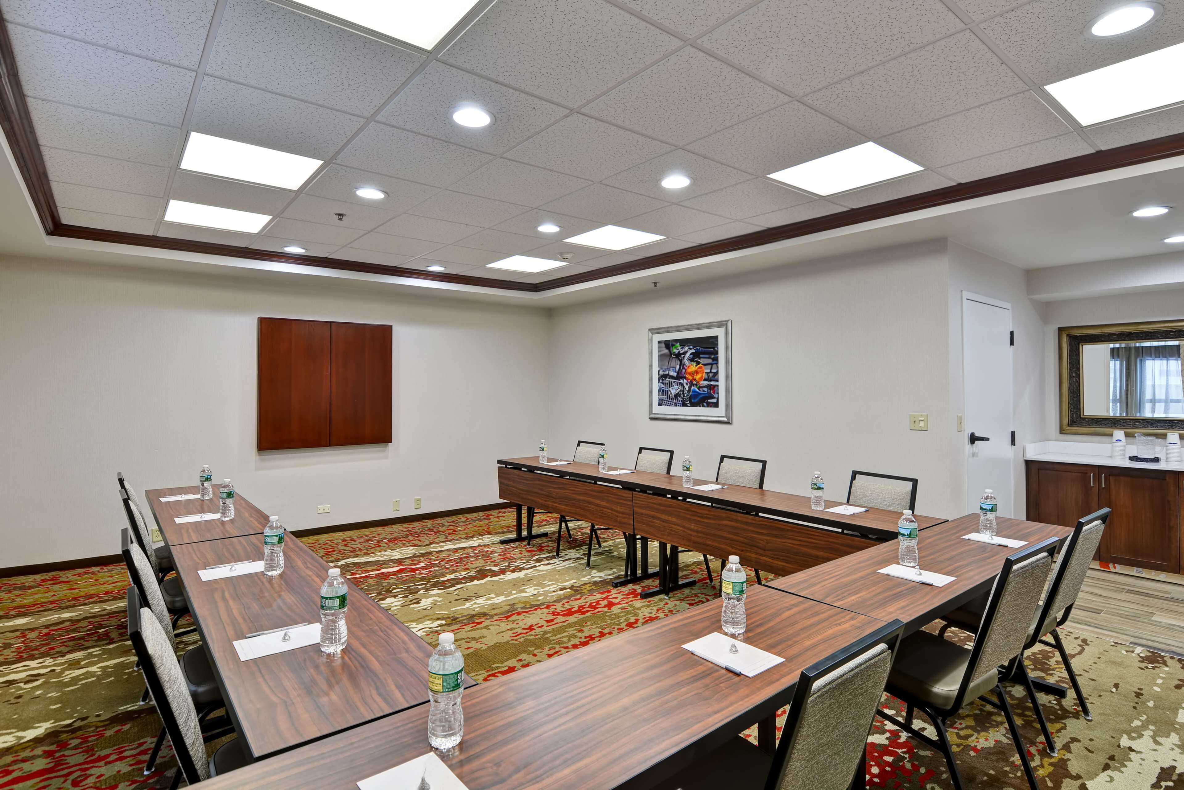 A conference room with a long table, chairs, water bottles, and a carpeted floor.