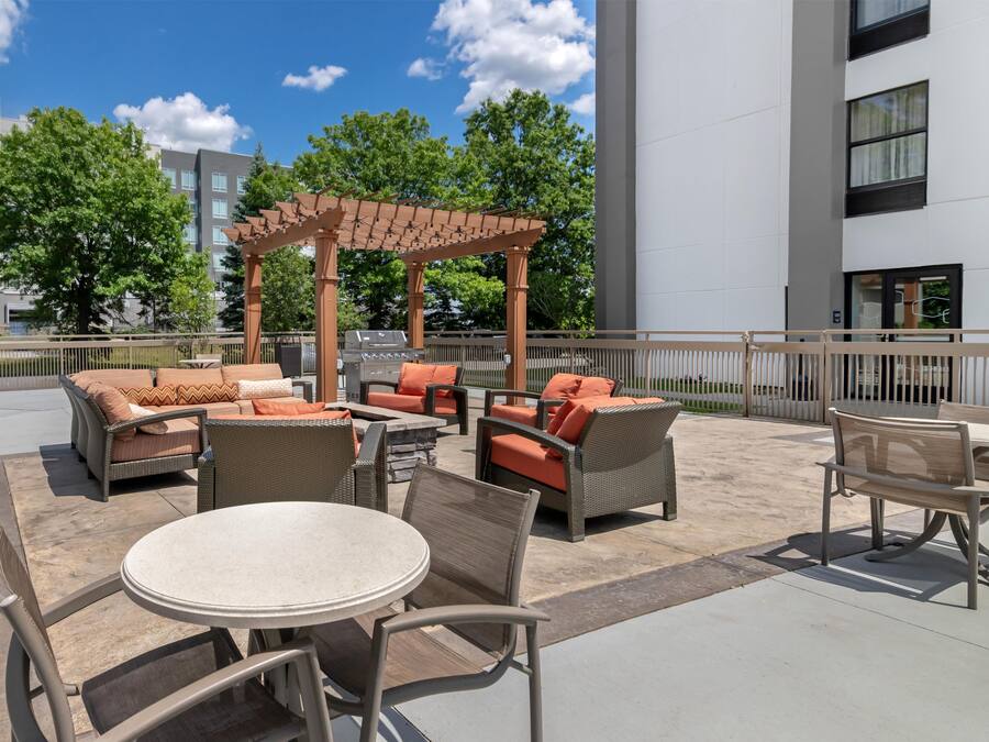 An outdoor patio area with wicker furniture, a pergola, and a barbecue grill.