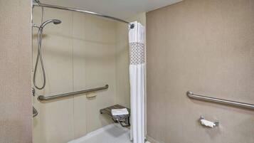A bathroom with a shower, grab bars, a towel rack, and a toilet.
