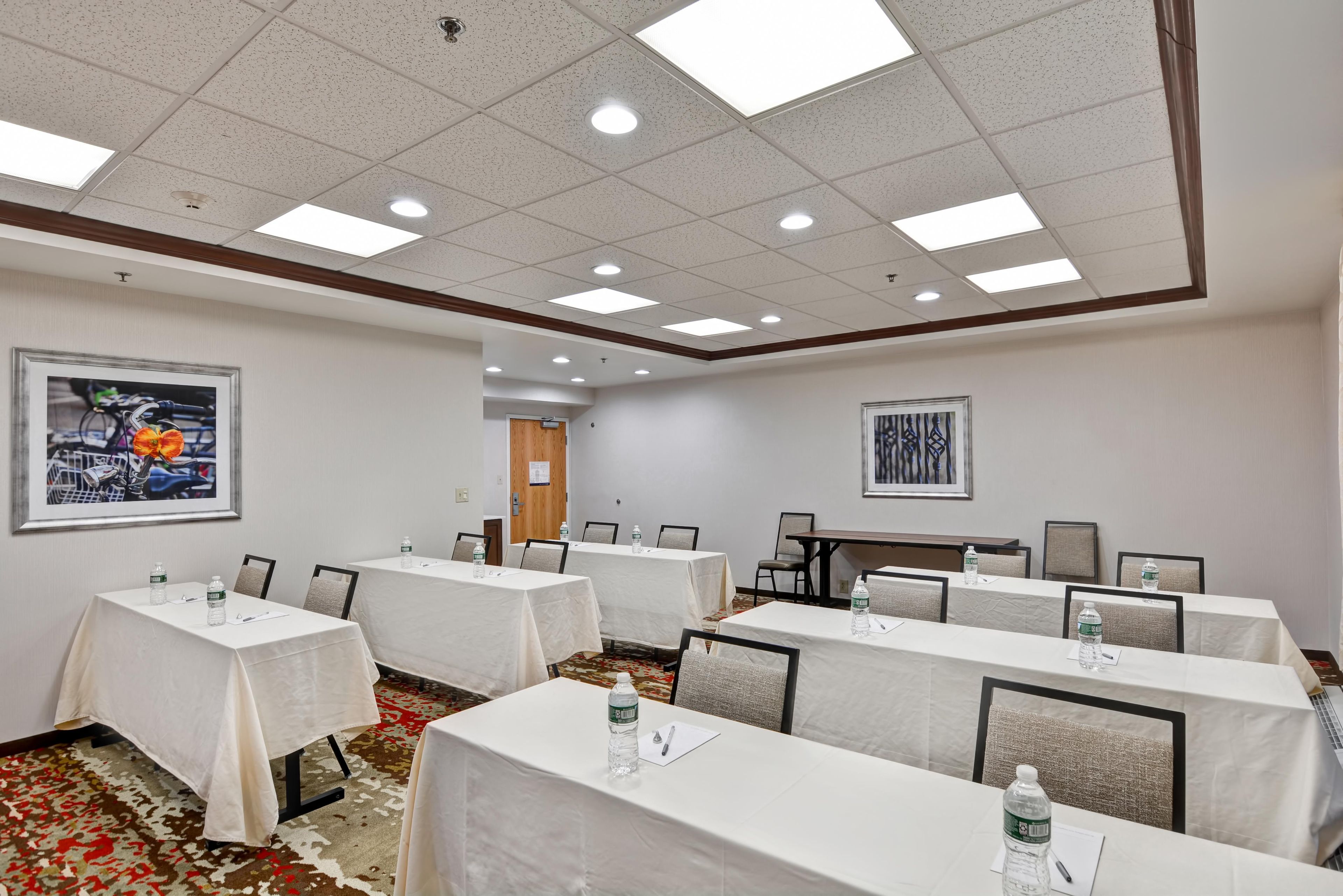 A conference room with multiple tables, chairs, and framed artwork on the walls.