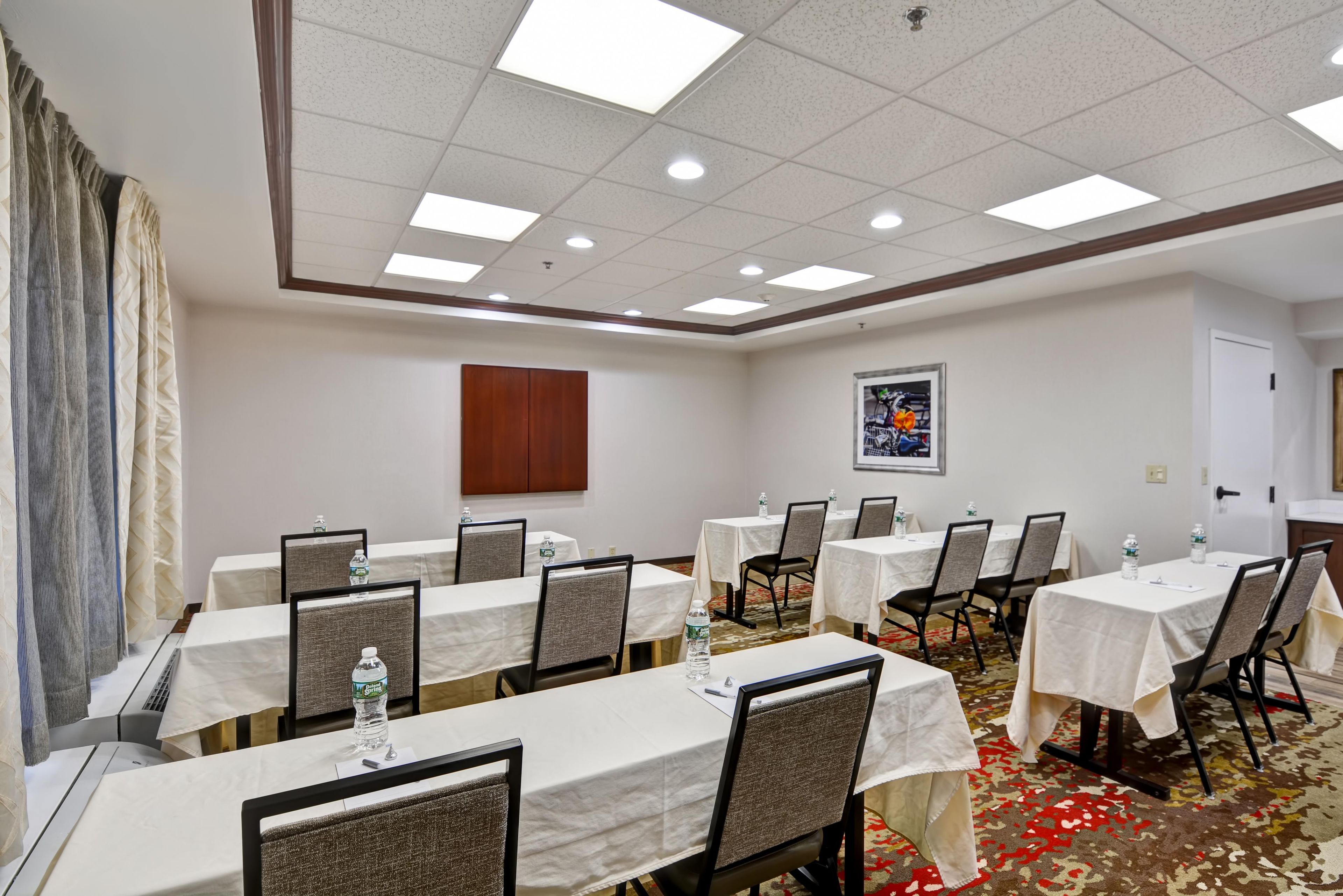 A conference room with multiple tables, chairs, and a carpeted floor.