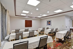 A conference room with multiple tables, chairs, and a carpeted floor. - Hampton Inn Albany-Wolf Road (Airport) (Albany)