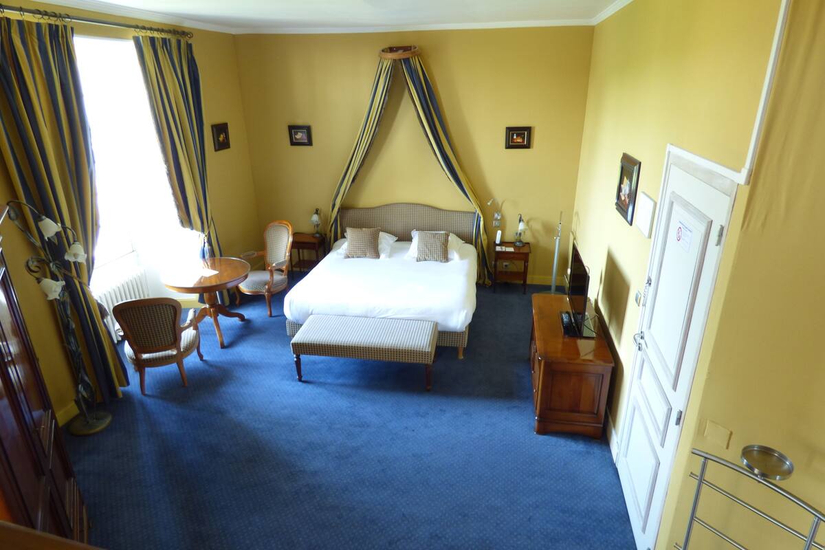 Een hotelkamer met een groot bed, een stoel, een klein tafeltje en een bureau.