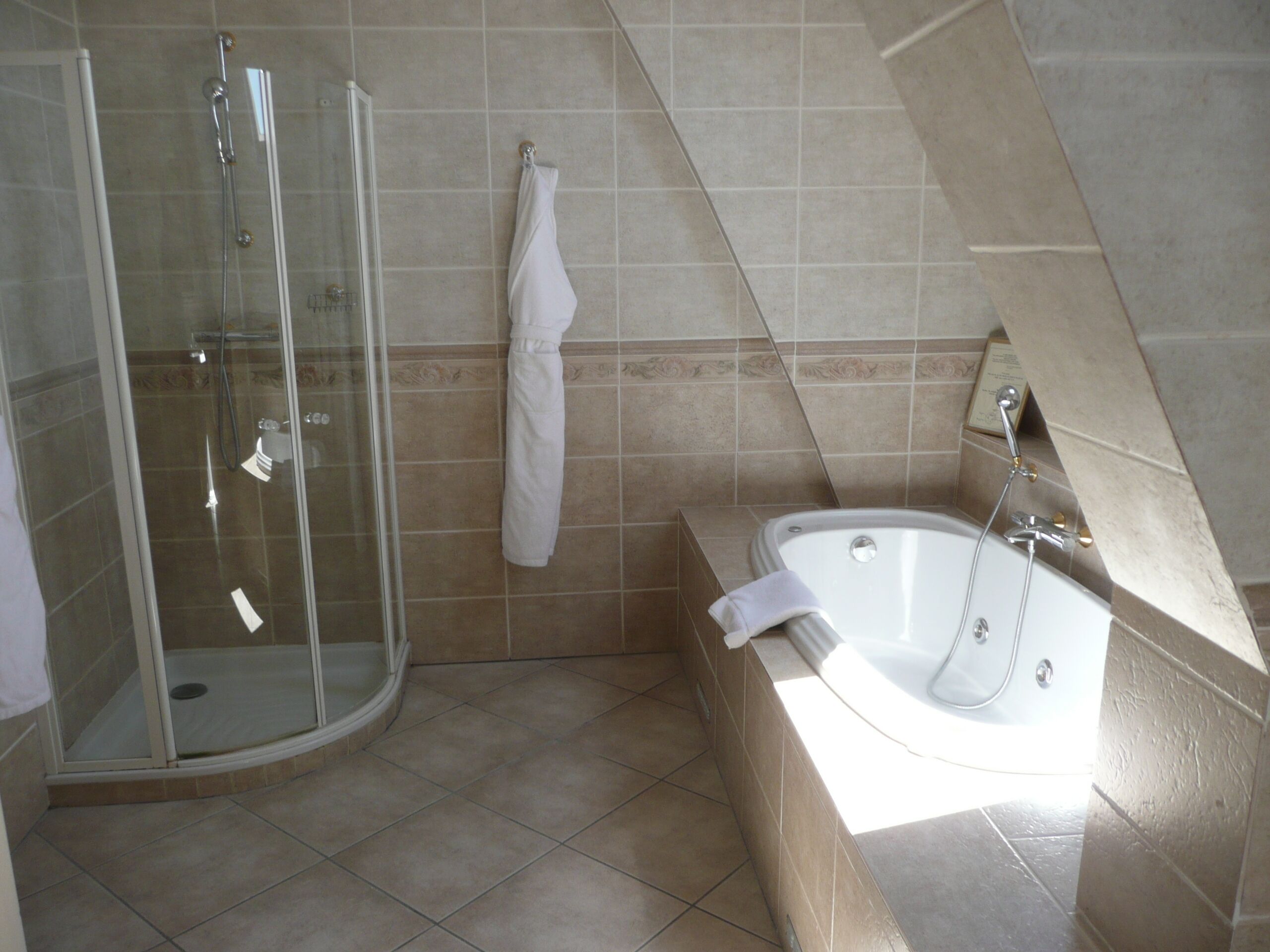 Een moderne badkamer met een douchecabine van glas, een bad en een handdoek aan de muur.
