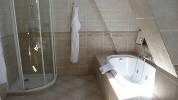 Een moderne badkamer met een douchecabine van glas, een bad en een handdoek aan de muur.