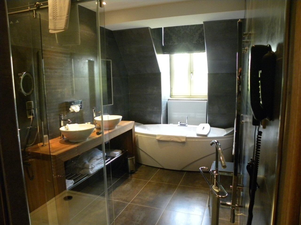 A modern bathroom with a glass-enclosed shower, a freestanding bathtub, and a vanity with two sinks.