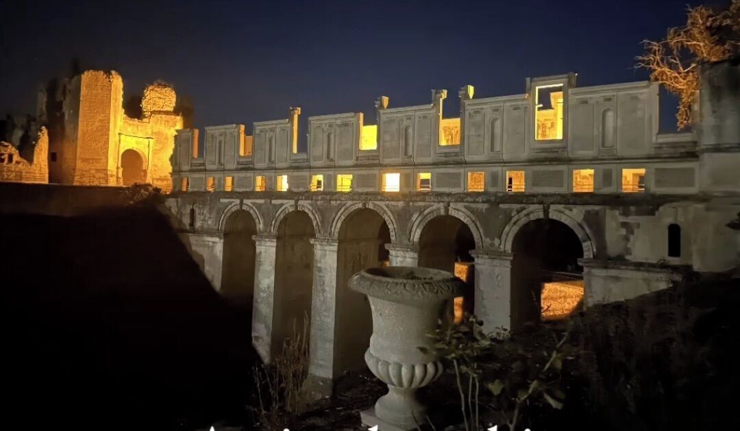A historic building with illuminated arches and a stone structure in the background.