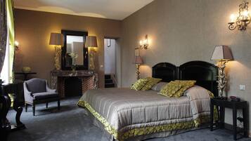 Ein Schlafzimmer mit einem großen Bett, einem Sessel, einem Kamin und Wandleuchten.