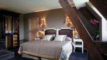 A bedroom with a large bed, two bedside tables with lamps, a wooden wardrobe, and a chair.