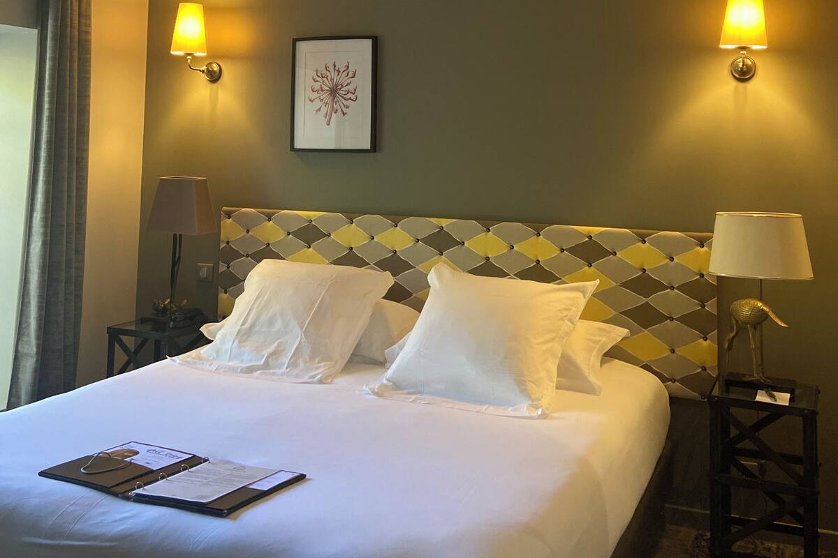 Hotelkamer met een bed, twee bedlampjes, een lijst aan de muur en een nachtkastje met lamp.
