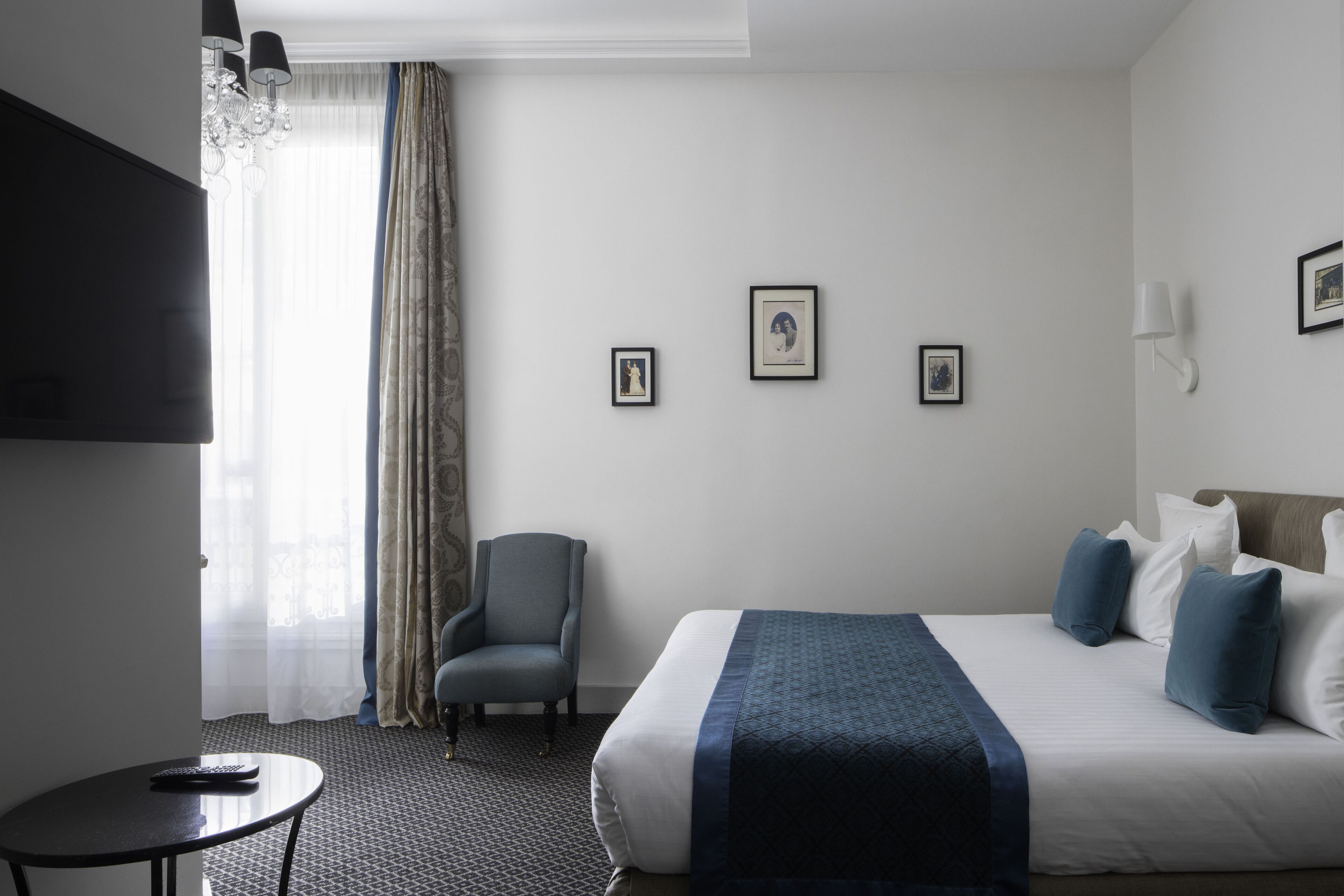 Una habitación de hotel con cama, una silla, una mesita y televisión.