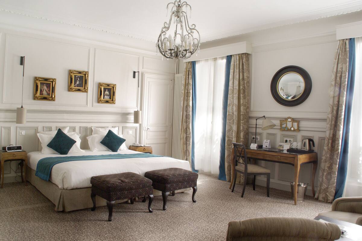 A well-appointed hotel room with a large bed, a desk, and a chair.