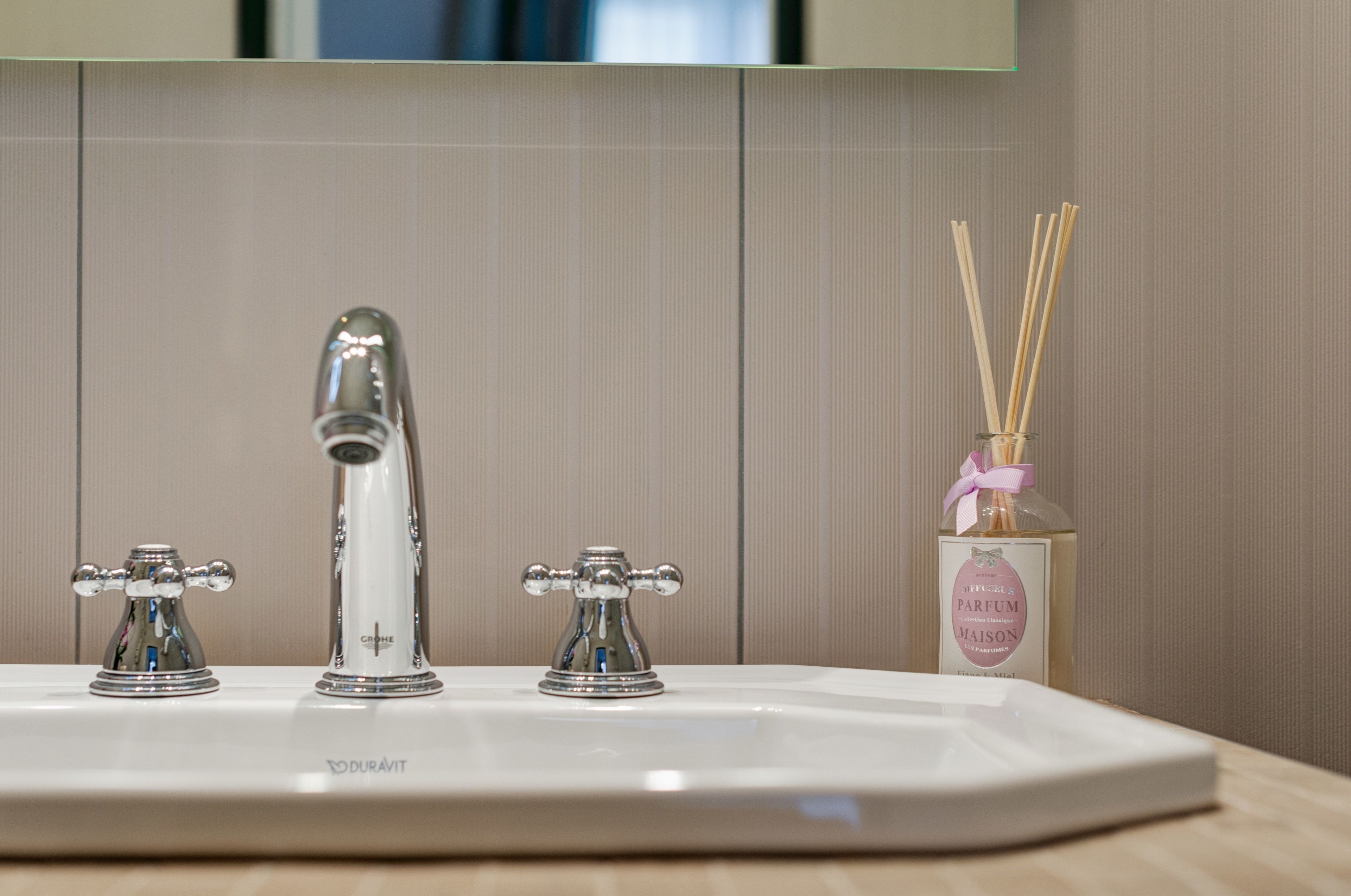 Un lavabo de salle de bain avec deux robinets et un flacon de parfum.
