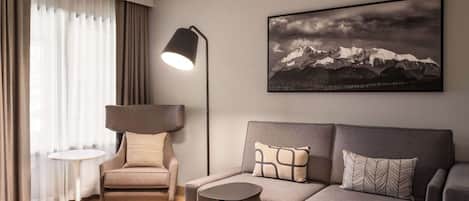 A modern living room with a sofa, a side table, a lamp, and a chair.