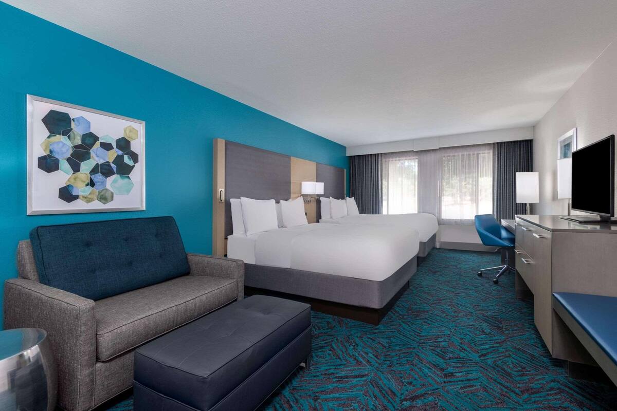 A hotel room with a large bed, a sofa, a desk, and a TV.