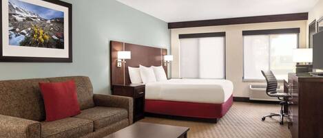 Quarto de hotel com cama, sofá, escrivaninha e cadeira.