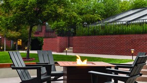 A patio area with a fire pit table and four Adirondack chairs. - Radisson Hotel Colorado Springs Airport (Colorado Springs)
