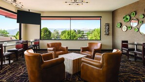 A hotel room with leather chairs, a table, a TV, and a large window with a city view. - Radisson Hotel Colorado Springs Airport (Colorado Springs)
