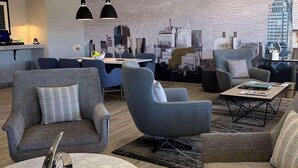 A modern living room with a cityscape mural, grey sofas, a marble coffee table, and pendant lighting. - Radisson Hotel Colorado Springs Airport (Colorado Springs)