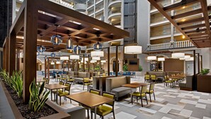 A spacious indoor area with multiple seating arrangements, including tables and booths, and a high ceiling with exposed beams and hanging lights.