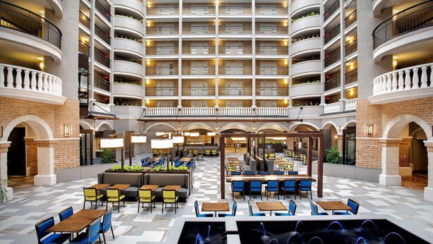 A multi-level hotel atrium with a checkered floor, multiple dining areas, and balconies.