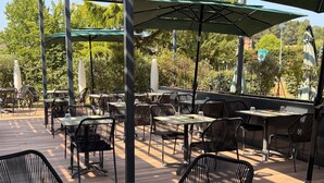 Un patio al aire libre con mesas y sillas, rodeado de follaje.