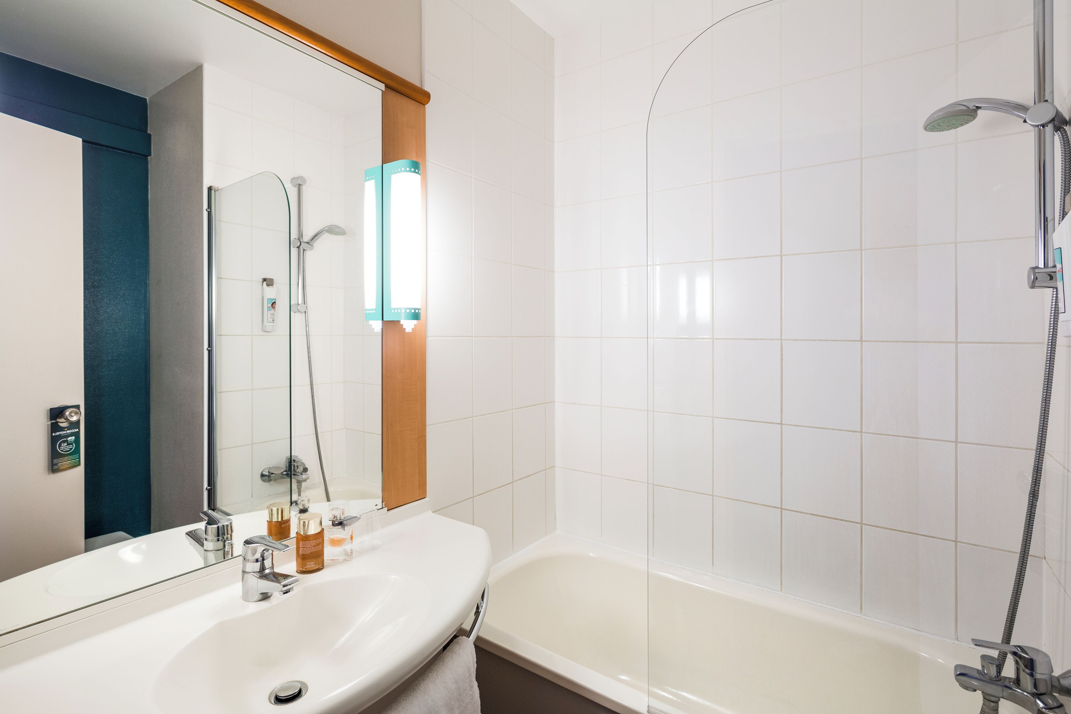A bathroom with a white sink, mirror, and shower.