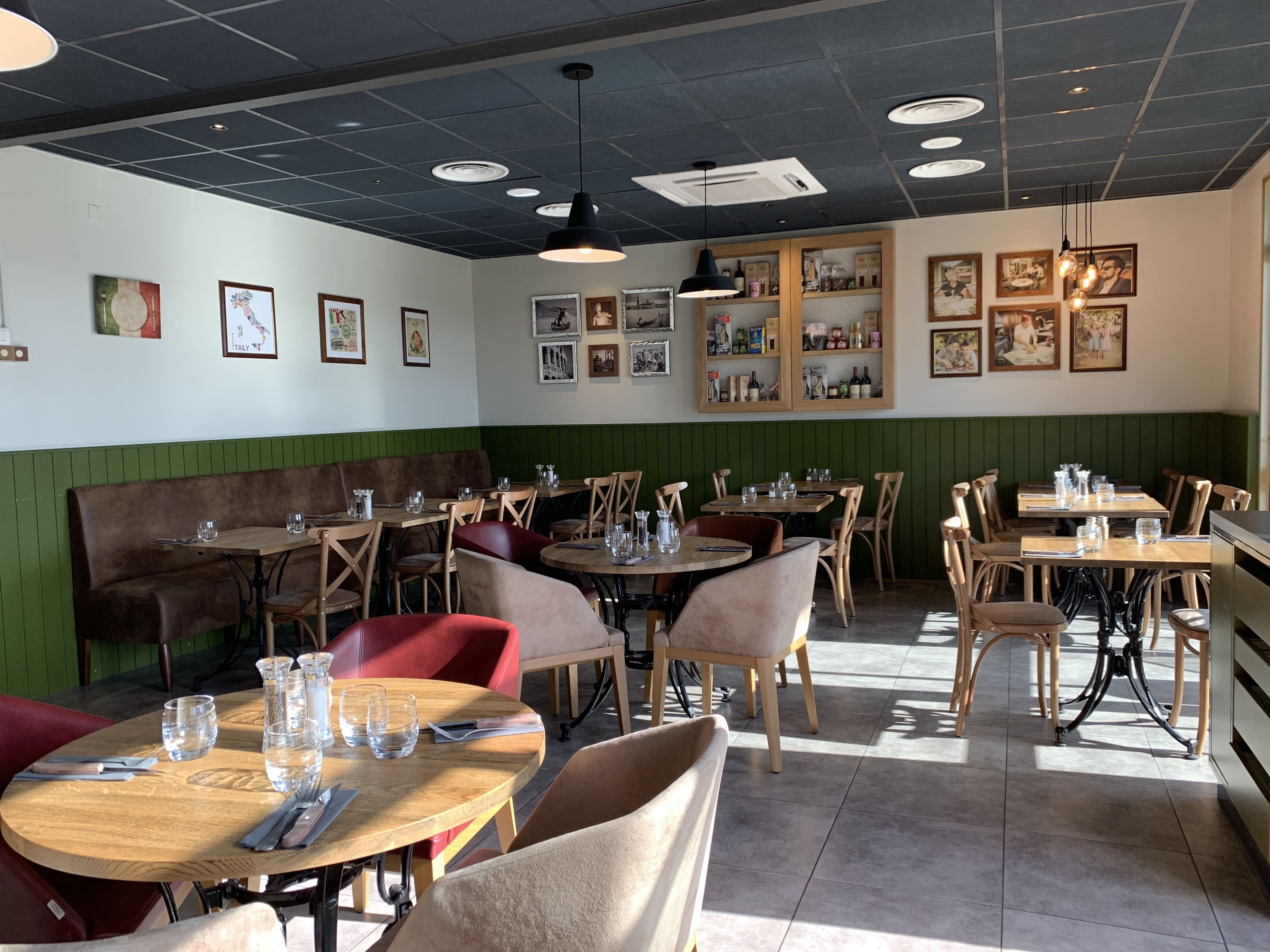 Interior de un restaurante con cabinas, mesas redondas y diversas fotografías enmarcadas en las paredes.