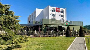 Un hotel con fachada blanca, toldo verde y un letrero que dice 'De Arte'.