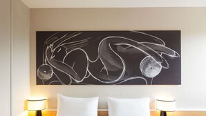 Habitación de hotel con dos camas, una gran obra de arte abstracta en la pared y lámparas de noche.