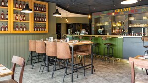 Interior de un restaurante con barra, sillas de madera y suelo de baldosas.