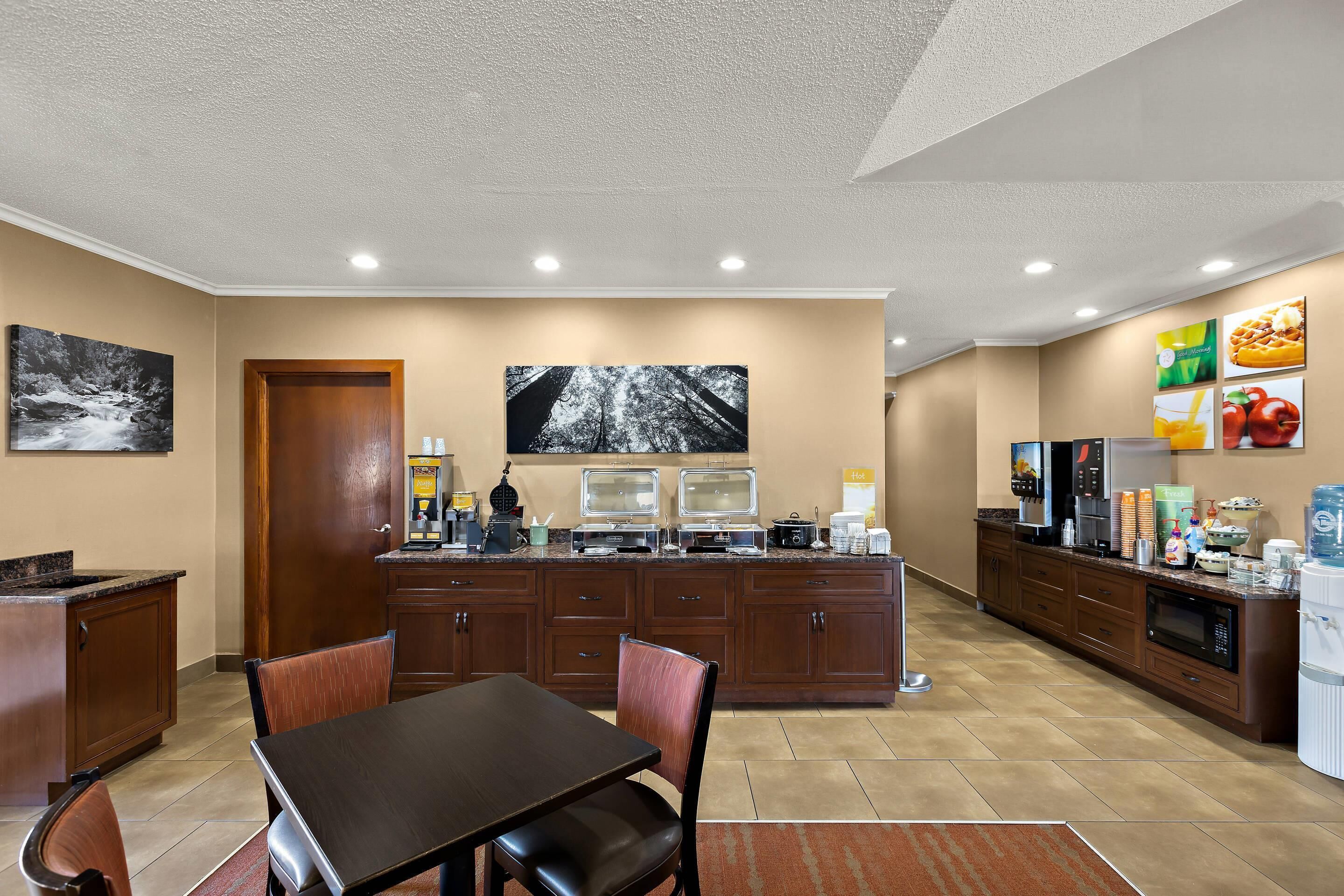A modern kitchen with a dining area, equipped with a coffee machine, microwave, and a large window.