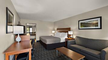 A hotel room with a bed, a desk, a chair, a sofa, and a picture on the wall.
