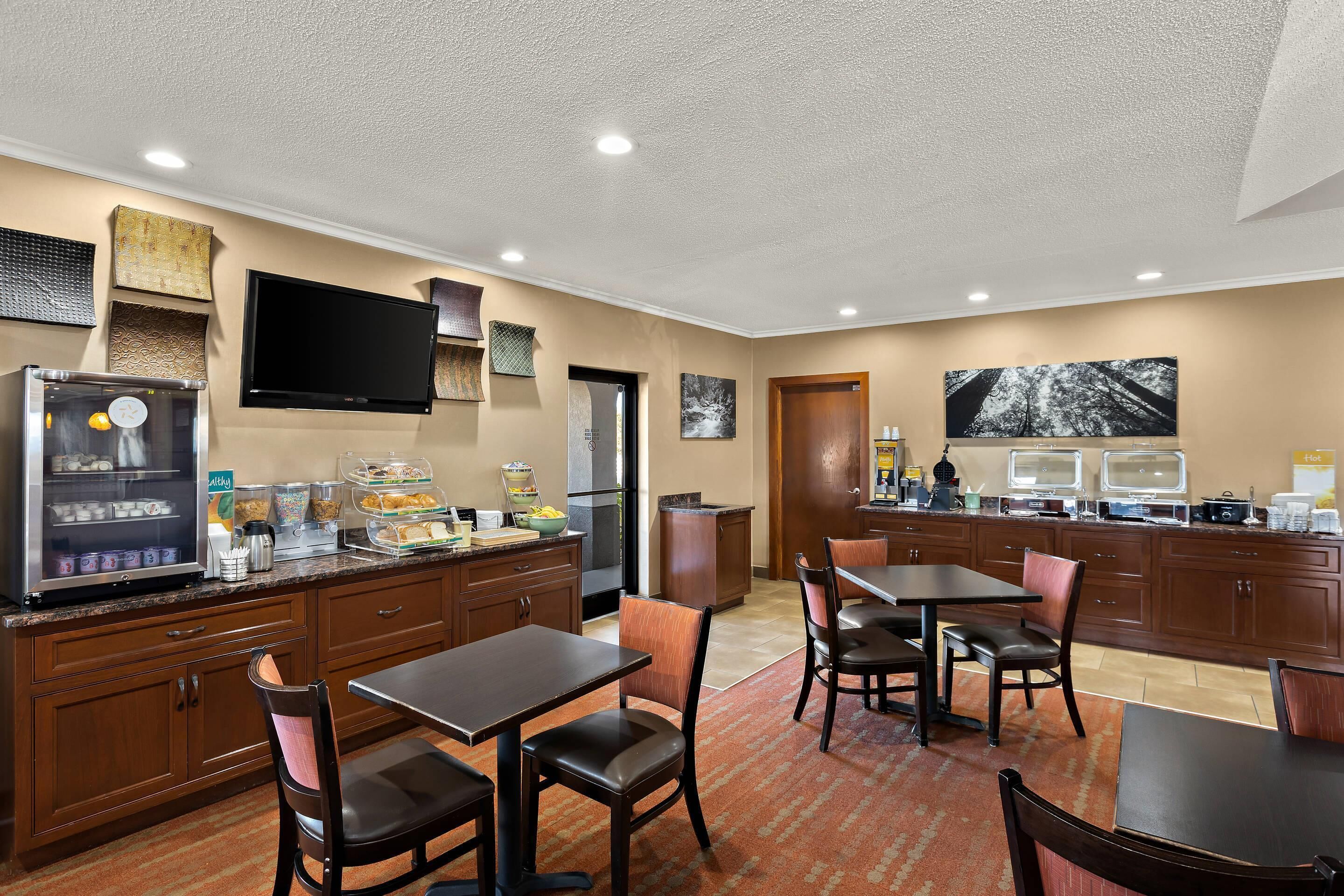 Cuina d'hotel amb nevera, microones i cafetera. Hi ha caires i taules per dinar.
