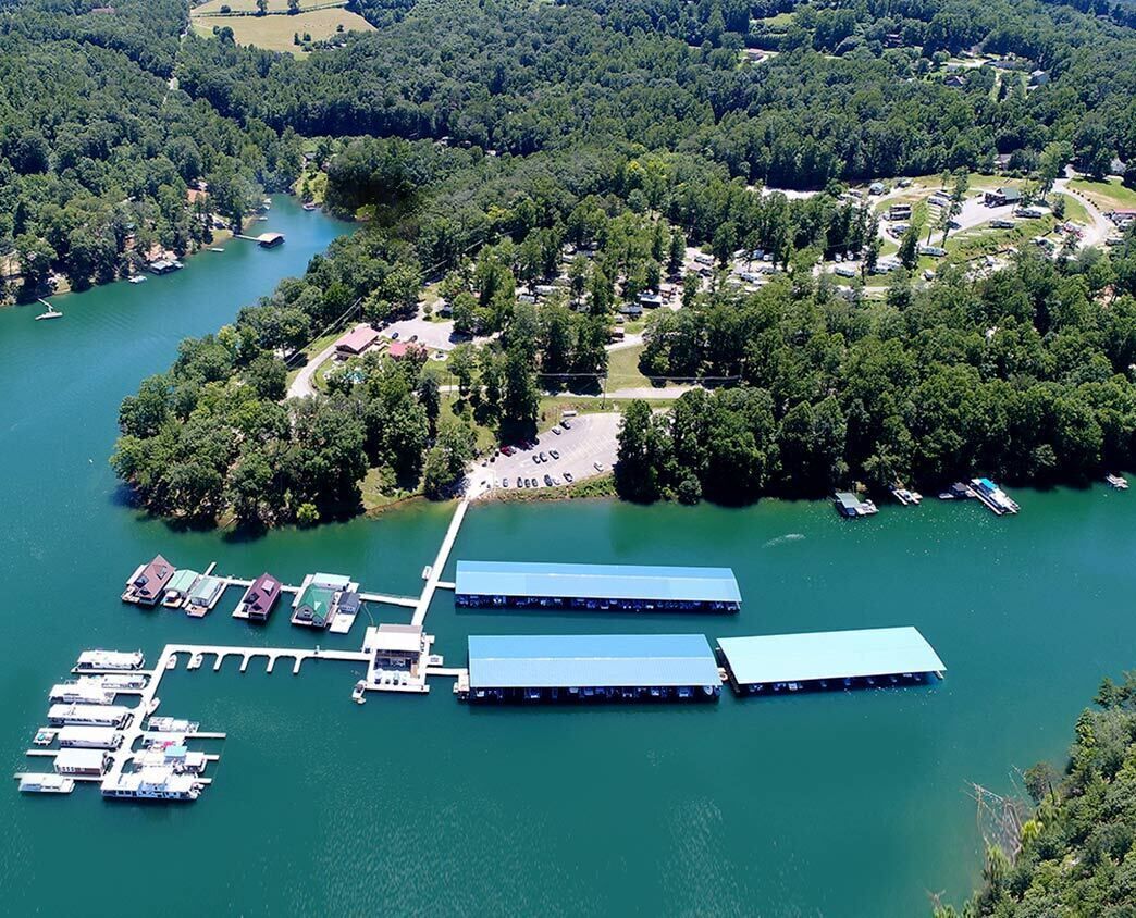 An aerial view of a lakeside property with docked boats, a pier, and a small building.