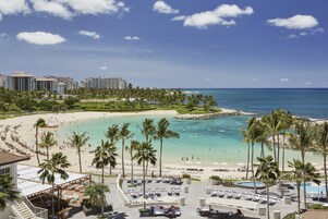 Un resort con playa, palmeras y zona de piscina.