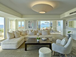 A spacious living room with a large sectional sofa, a coffee table, and a view of the ocean through large sliding doors.