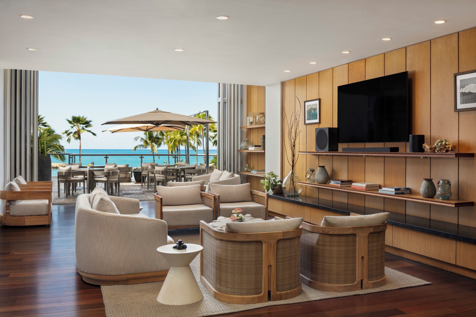 A modern living room with a view of the ocean, furnished with sofas and a TV.
