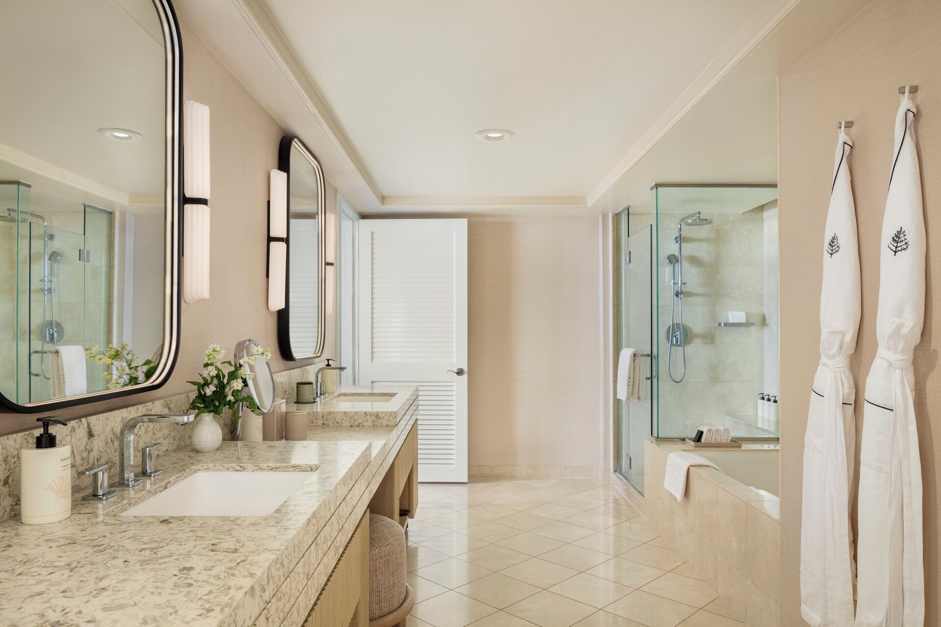 A modern bathroom with a double sink, large mirrors, a glass shower enclosure, and white towels.