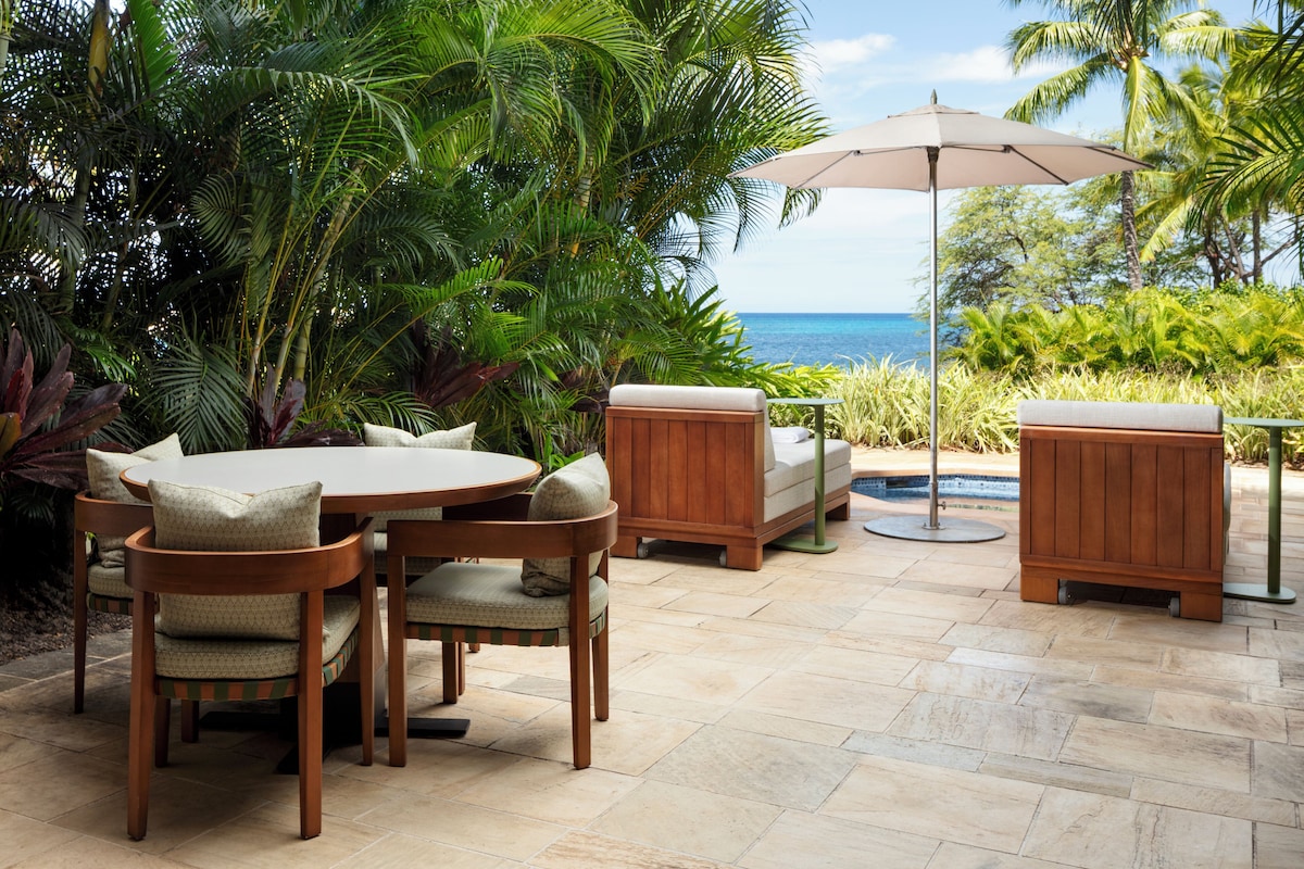 Un patio exterior con una mesa redonda, sillas, un sofá acolchado y un armario de madera.