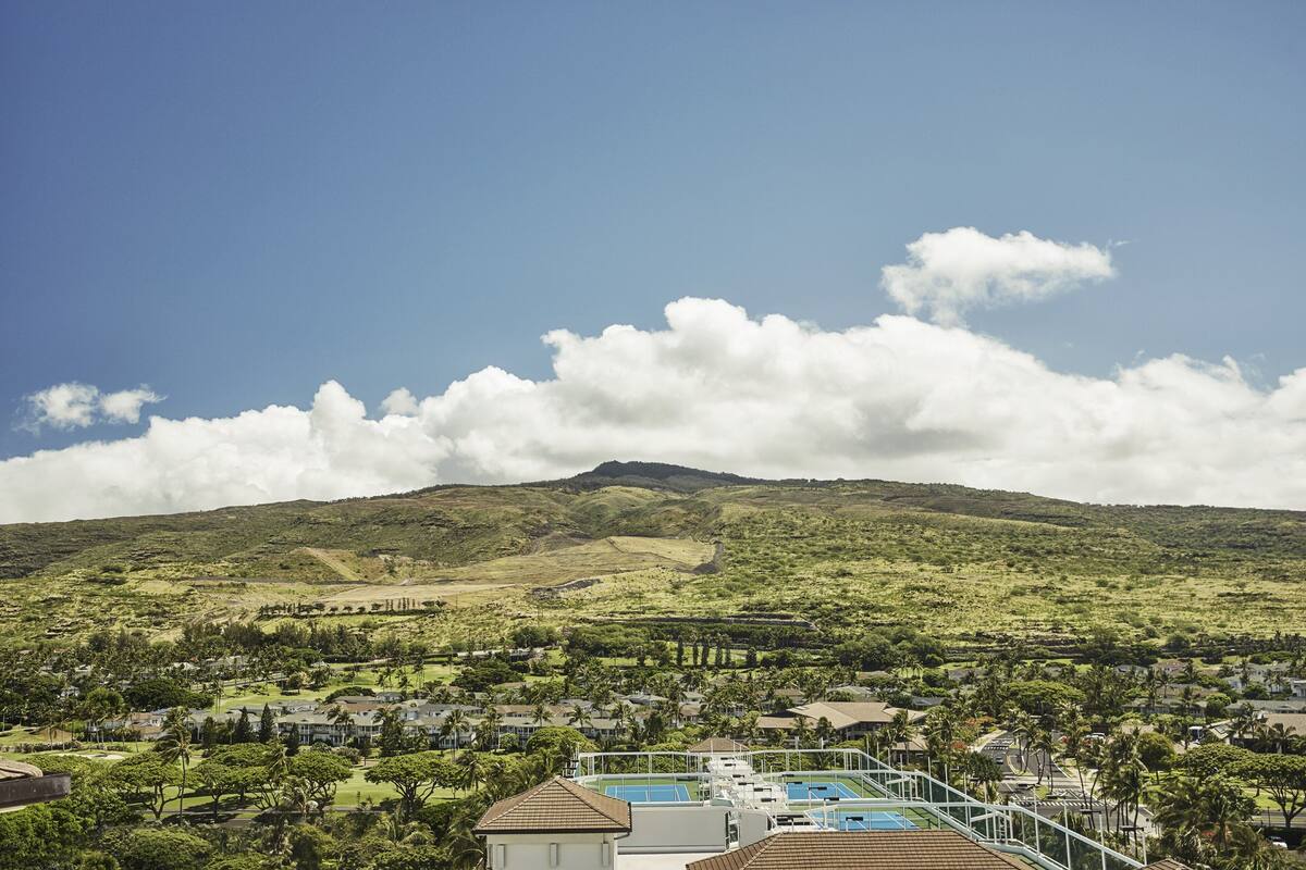 Ein Resort mit Poolbereich, üppiger Vegetation und einem Berg im Hintergrund.