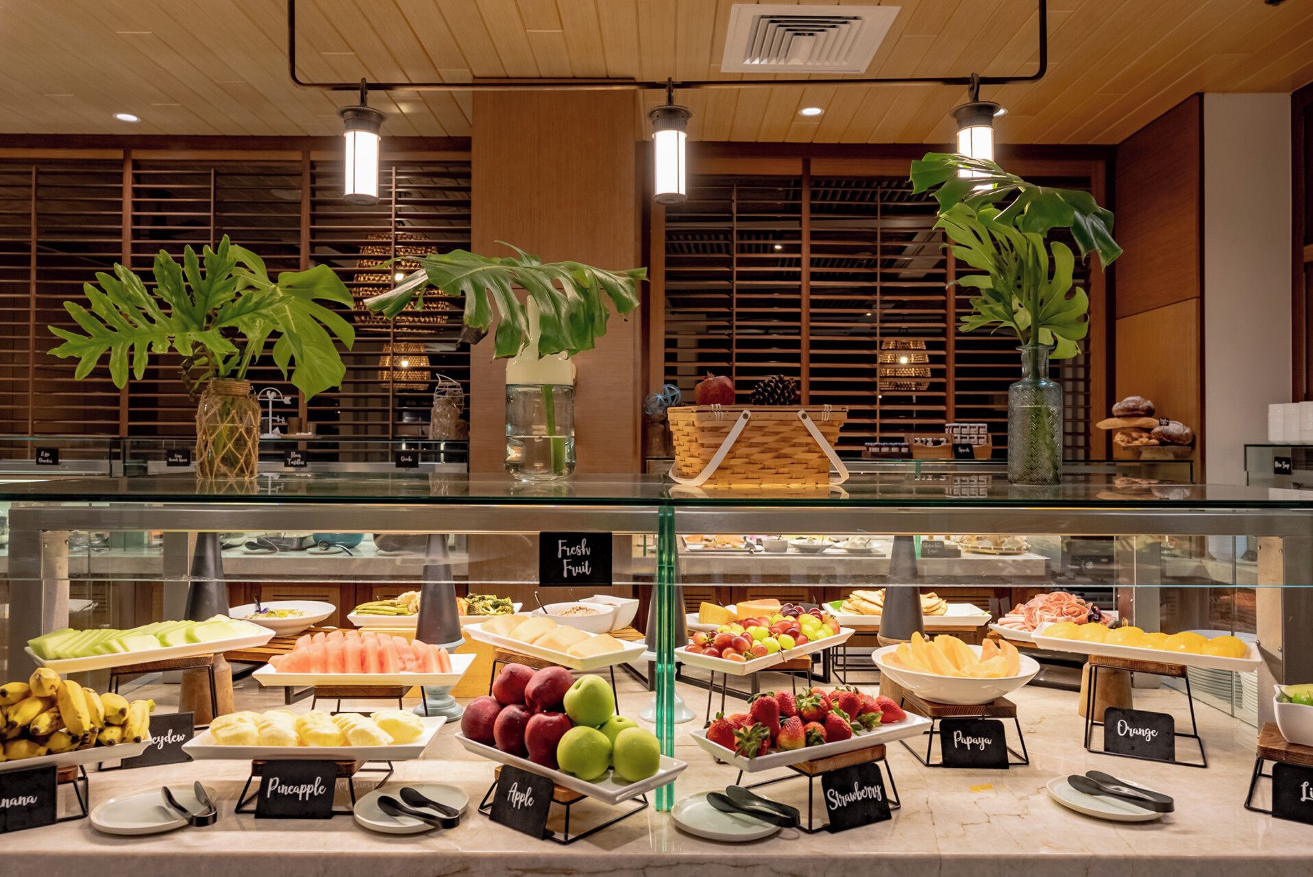 Ein Buffetbereich mit verschiedenen Früchten und Backwaren, präsentiert vor einer Glasvitrine.
