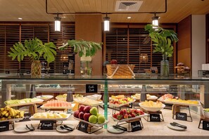 A buffet area with various fruits and pastries displayed in front of a glass case. - Four Seasons Resort Oahu at Ko Olina (Kapolei)