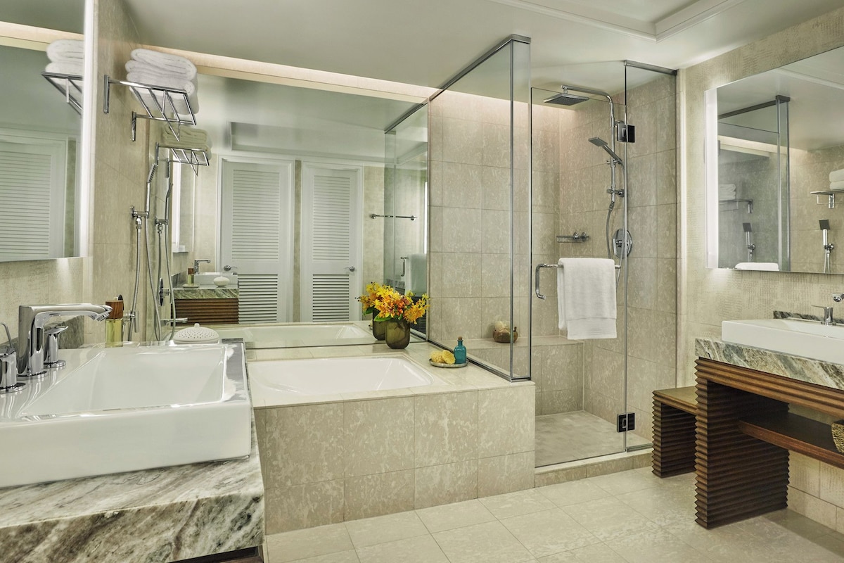 Un baño moderno con dos lavamanos, cabina de ducha de vidrio y un espejo grande.