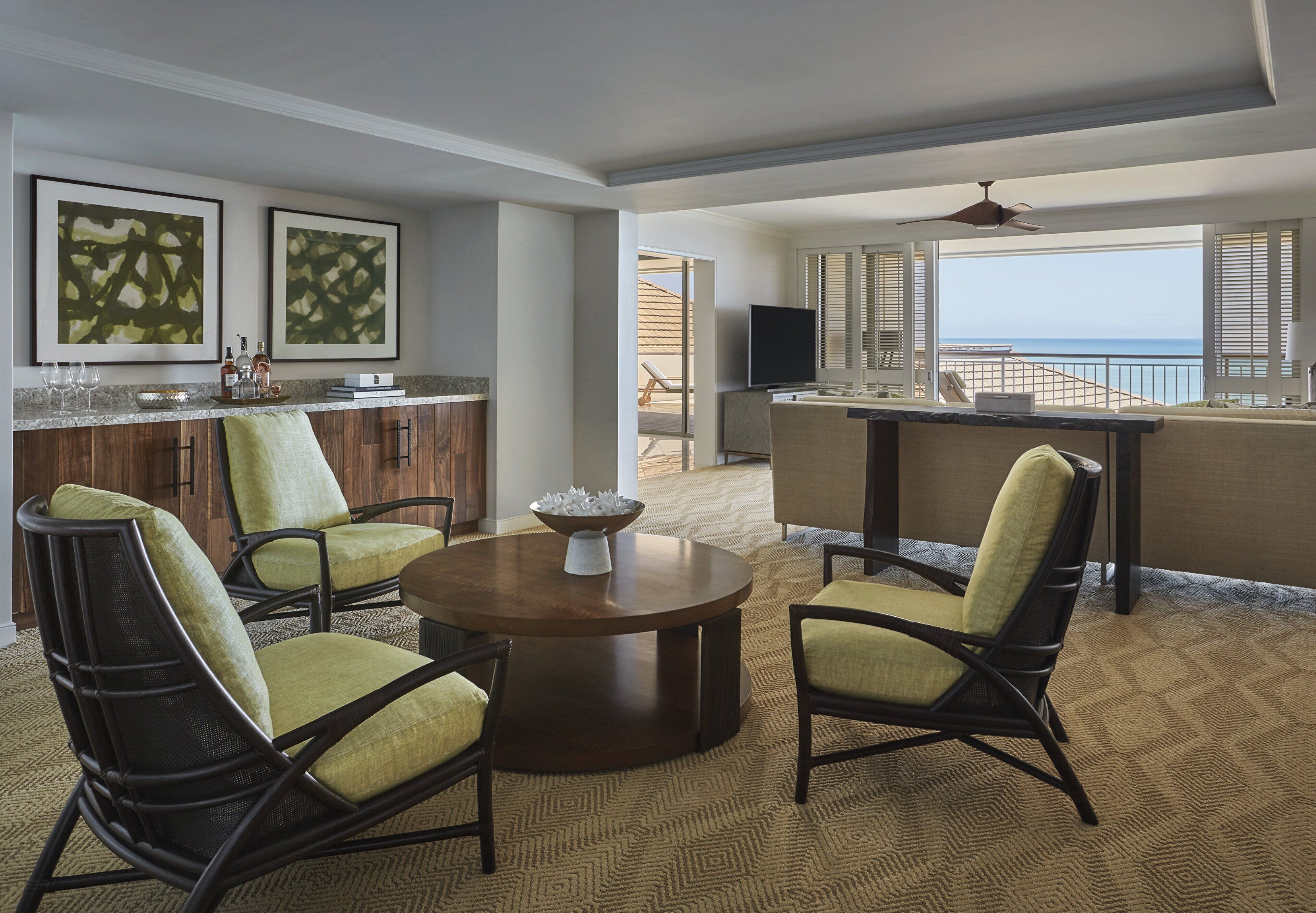 A dining area with a round table and chairs, a kitchen with a bar, and a view of the ocean.