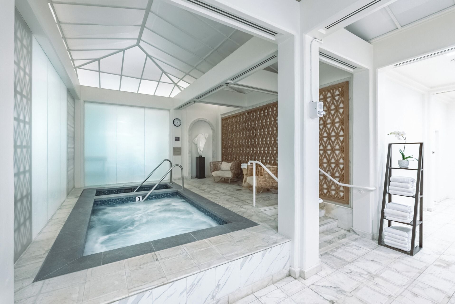 A spa room with a hot tub, seating area, and a towel rack.