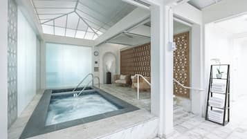 A spa room with a hot tub, seating area, and a towel rack.