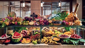 Une présentation de fruits et de légumes dans un restaurant, avec une variété de fruits tropicaux, de légumes et de noix.